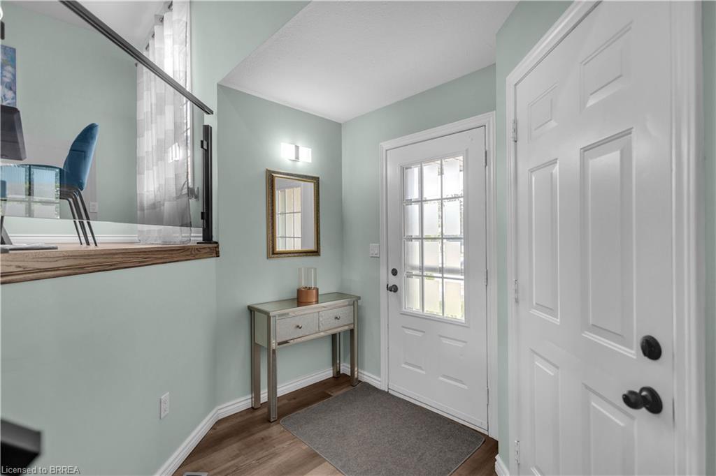 Entryway featuring wood-finish flooring, a white paneled door with black hardware, and a glass-paneled entry door
