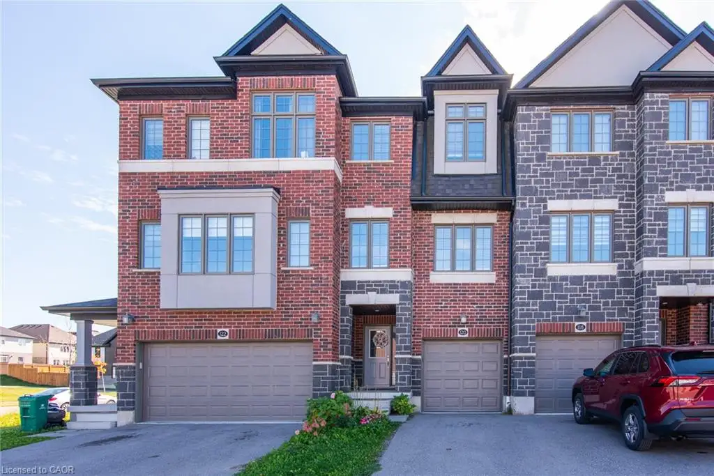Red brick and stone facade with multiple window styles, featuring a bay window and individual garage doors