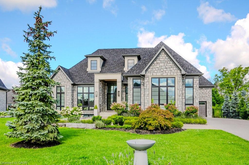 French provincial home with stone siding, a front yard, and a shingled roof