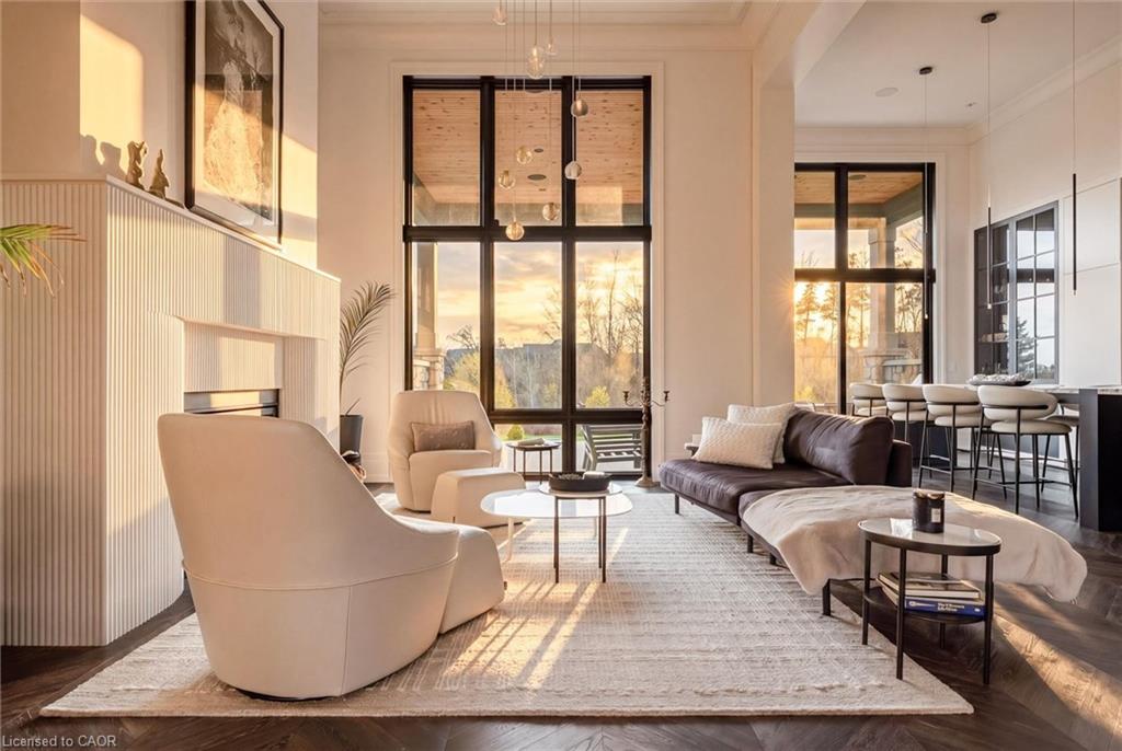 Living area featuring expansive floor-to-ceiling windows, a built-in linear fireplace, high ceilings with crown molding, and dark wood-finish flooring