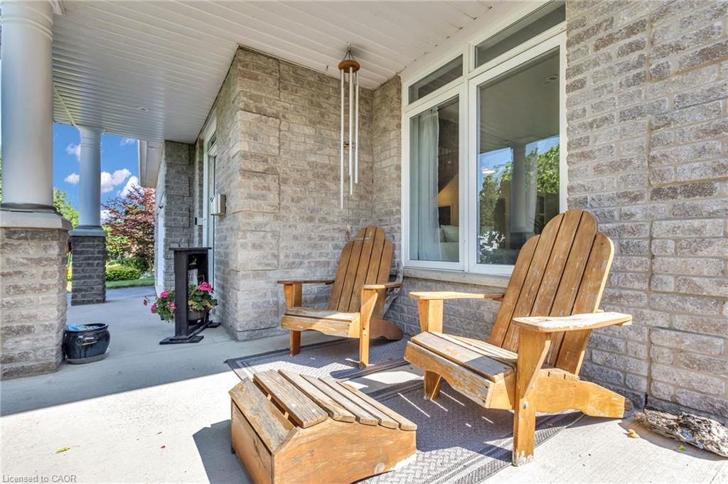 Covered front porch featuring a stone-clad exterior, white structural columns, and large windows
