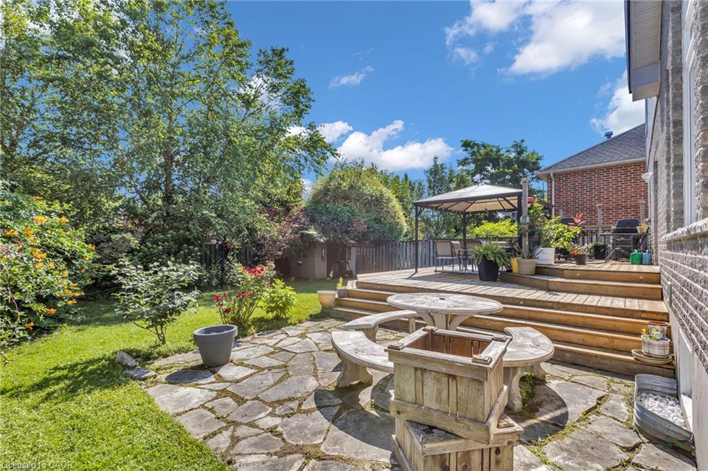 Expansive backyard featuring a multi-level wood deck, stone patio, and mature trees
