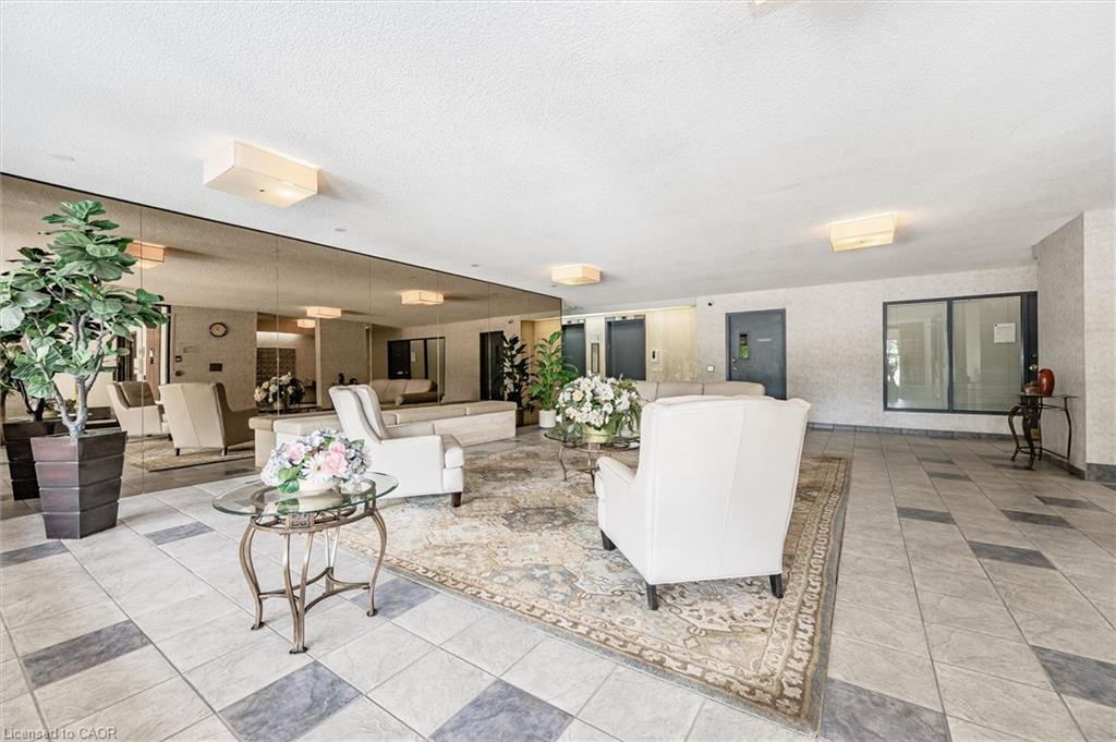 Spacious lobby featuring a patterned area rug, neutral tiled flooring, full-wall mirrored accents, and recessed ceiling lighting