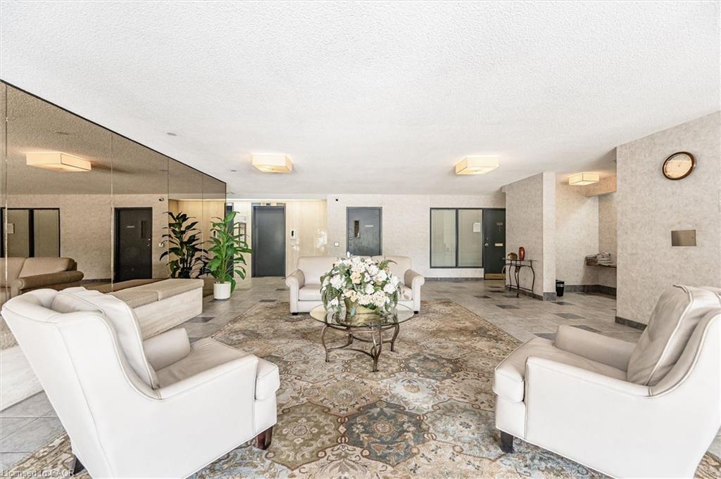 Spacious lobby featuring a patterned area rug, neutral tiled flooring, full-wall mirrored accents, and recessed ceiling lighting