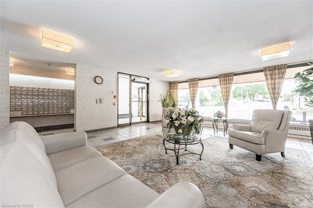 Spacious lobby featuring a patterned area rug, neutral tiled flooring, full-wall mirrored accents, and recessed ceiling lighting