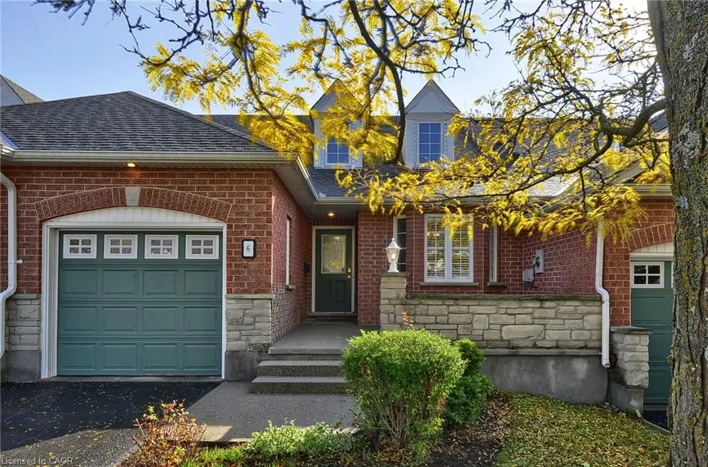 Red brick exterior with stone veneer accents, multi-paneled garage doors, dual dormer windows, and a concrete entry porch