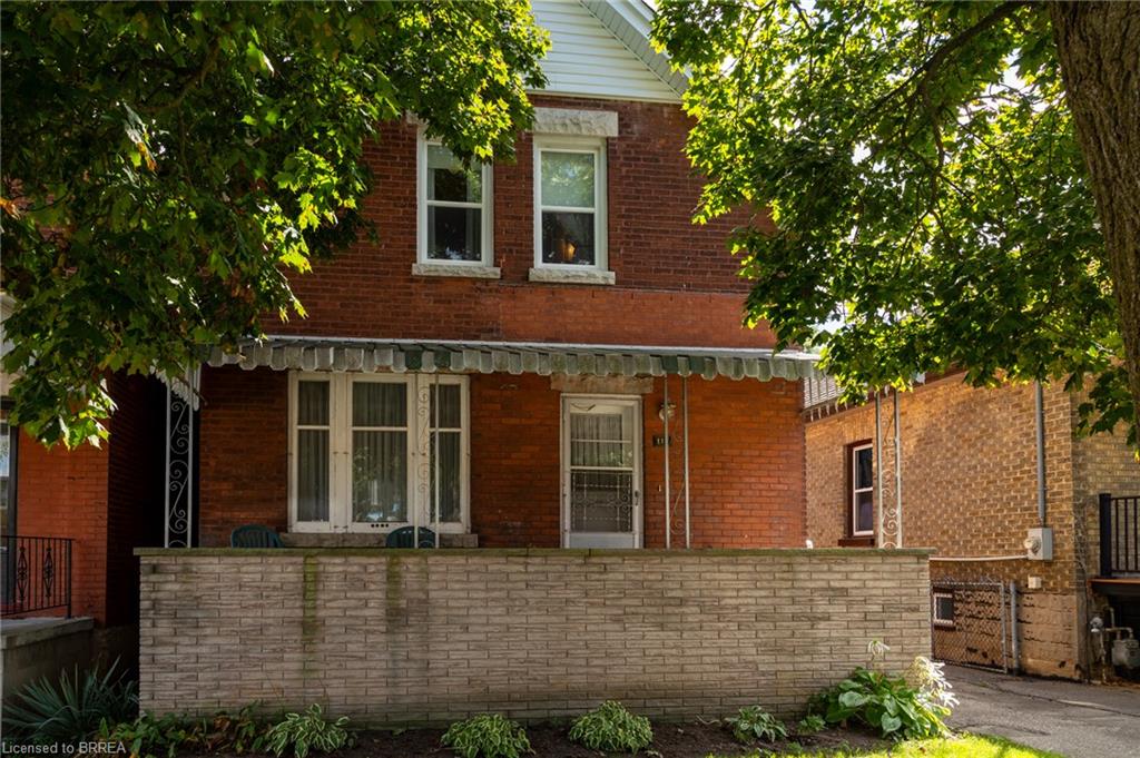 Brick exterior with white window trim, a covered front porch, and a decorative awning