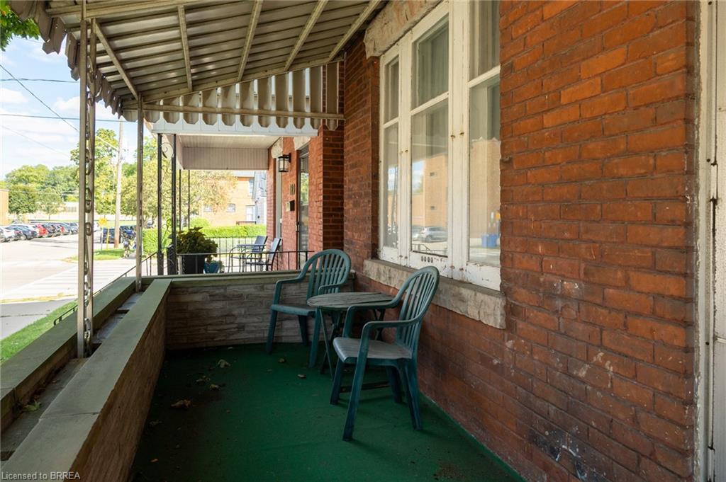 Brick exterior featuring a covered porch with a metal awning and decorative railing