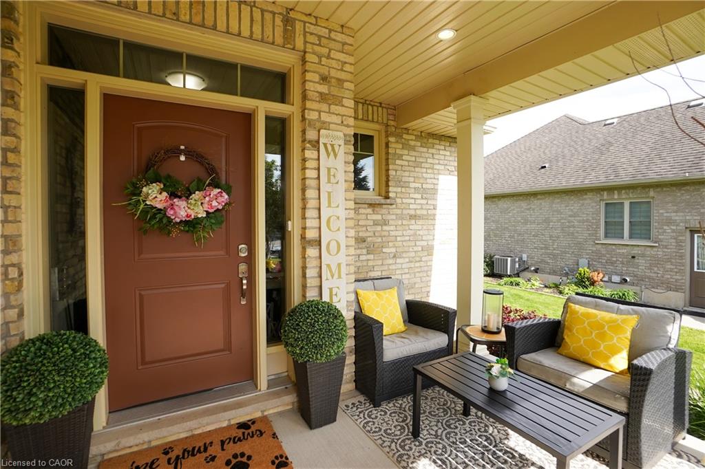 Covered front porch featuring a brick exterior and a brown front door with sidelights