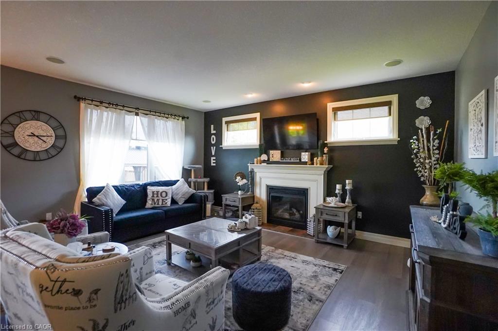 Living area featuring wood-finish flooring, a white mantel fireplace, and recessed ceiling lighting