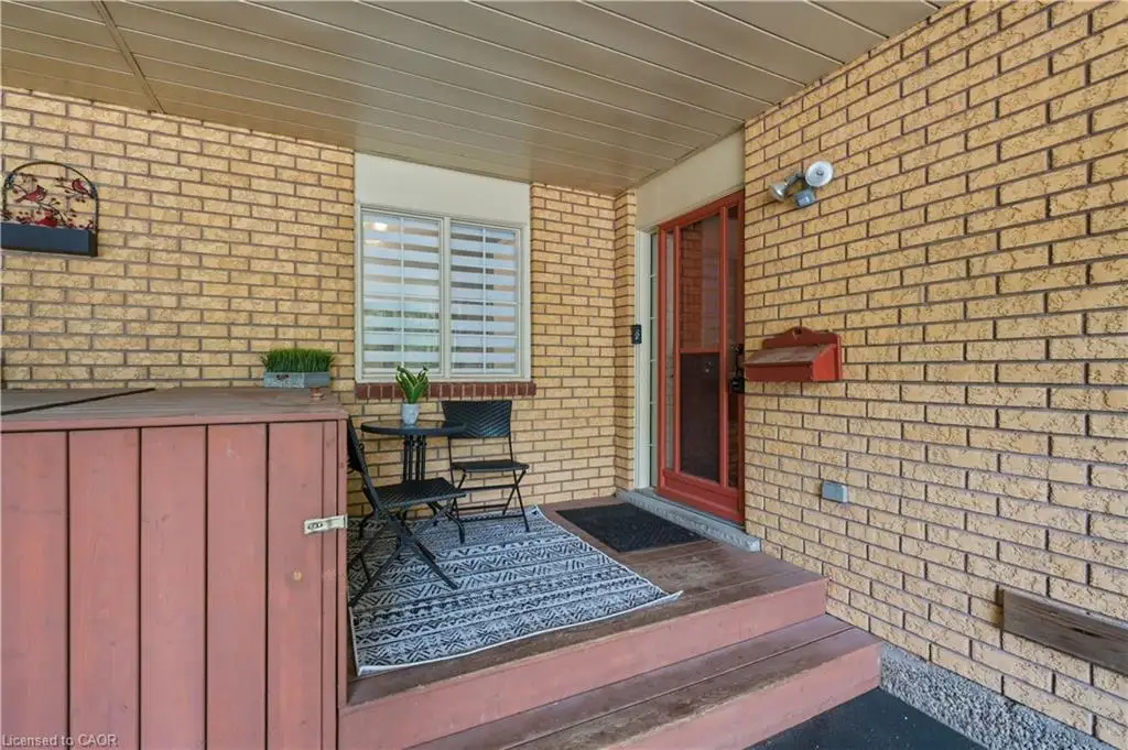 Brick exterior with covered porch, wood-tone steps, and a red-framed entry door
