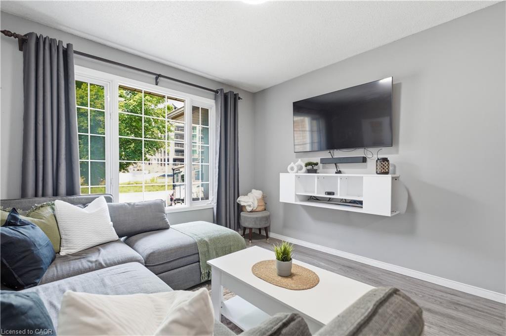 White-framed windows with grid patterns, light gray walls, wood-finish flooring, and a floating media console