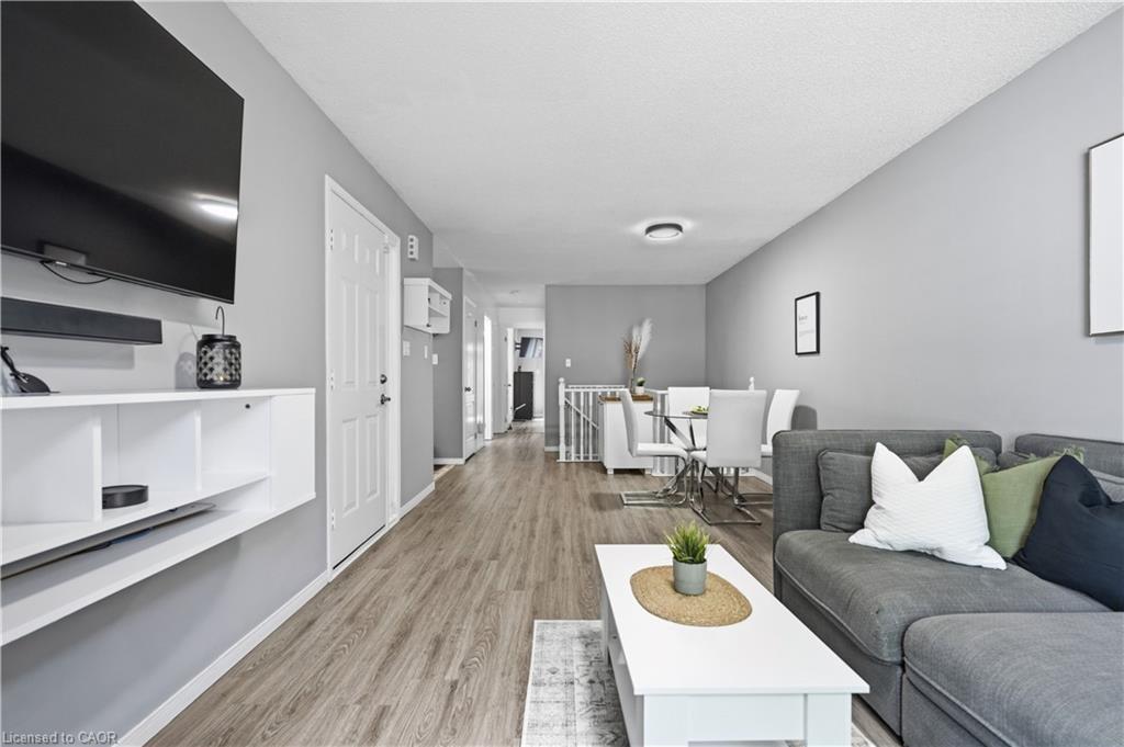 Open-concept living area with wood-finish flooring, neutral gray wall tones, and recessed ceiling lighting