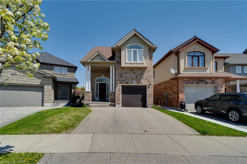 Brick facade residence featuring a prominent arched entry, a two-car garage, and a concrete driveway