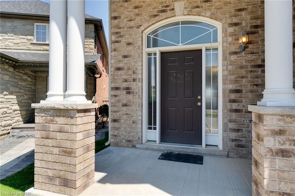 Brick facade entrance featuring a dark paneled door with sidelights, an arched transom window, and a concrete porch
