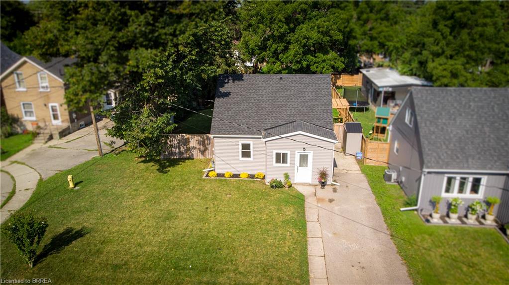 Light gray siding exterior with a dark shingle roof, established front lawn, and paved driveway
