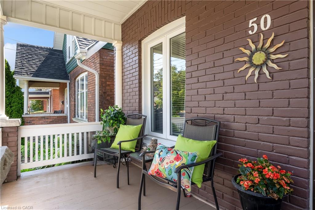 Covered front porch featuring a brick facade, white railings, and column supports