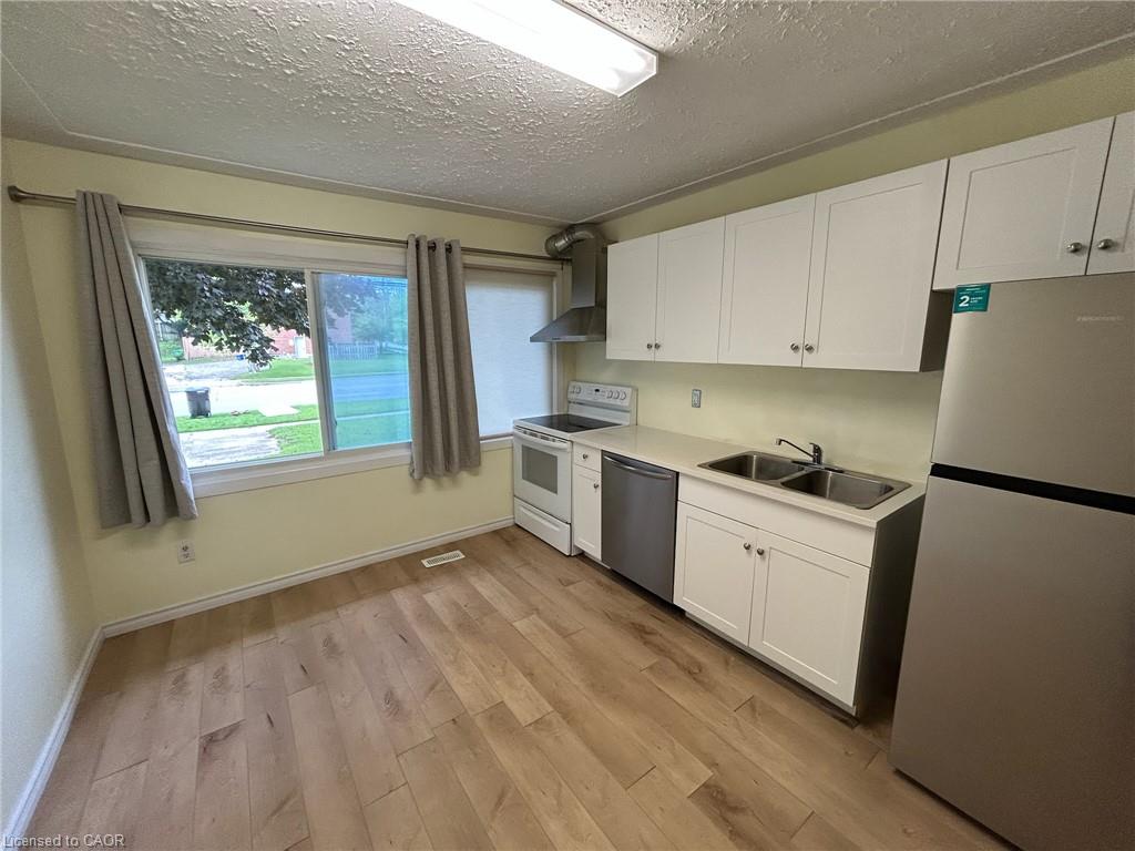 Kitchen featuring wood-finish flooring, white cabinetry, a stainless steel sink, and stainless steel appliances