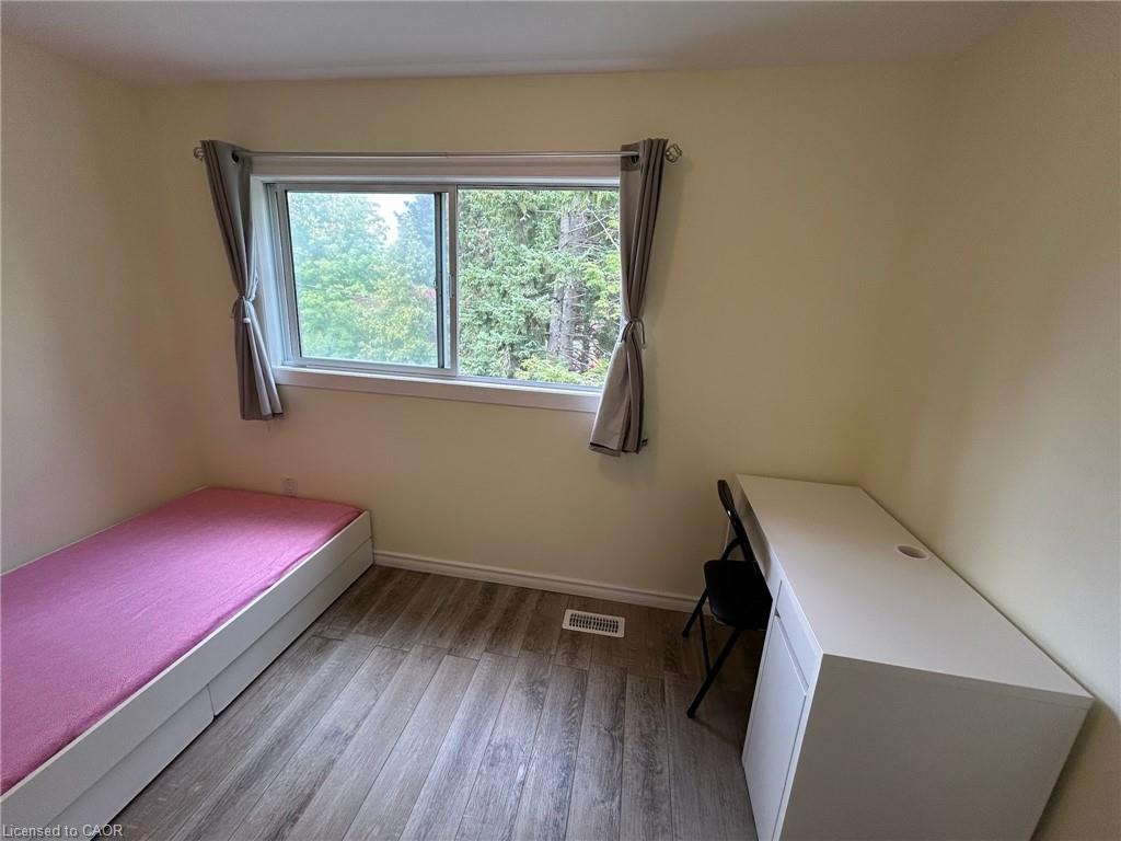 Wood-finish flooring with white baseboards and a large window