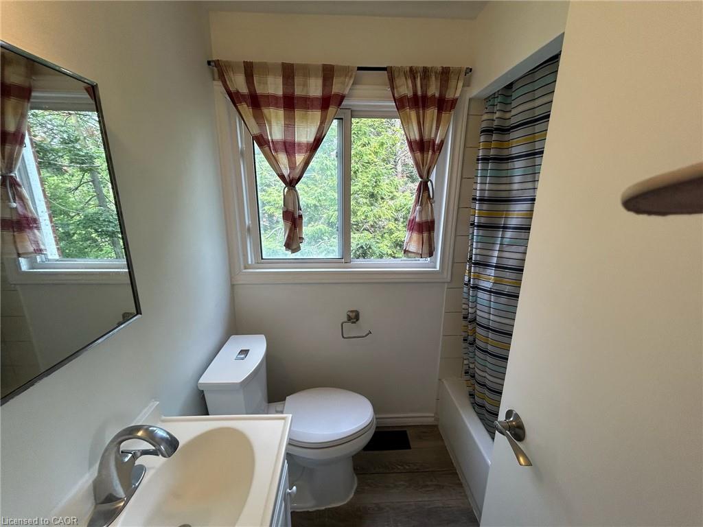 Vanity with integrated sink and chrome faucet, white toilet, and window with natural light