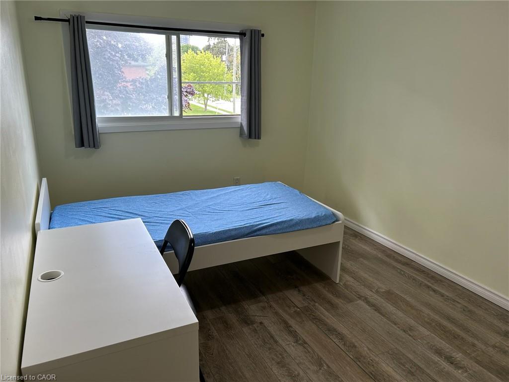 Window with grey panel drapes, wood-finish flooring, and light-colored walls