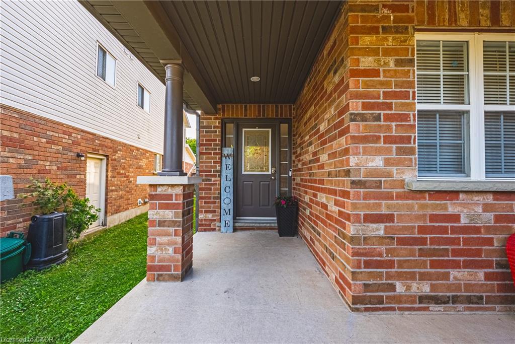 Front entrance featuring a covered concrete porch, brick facade, and a dark-paneled door with decorative glass