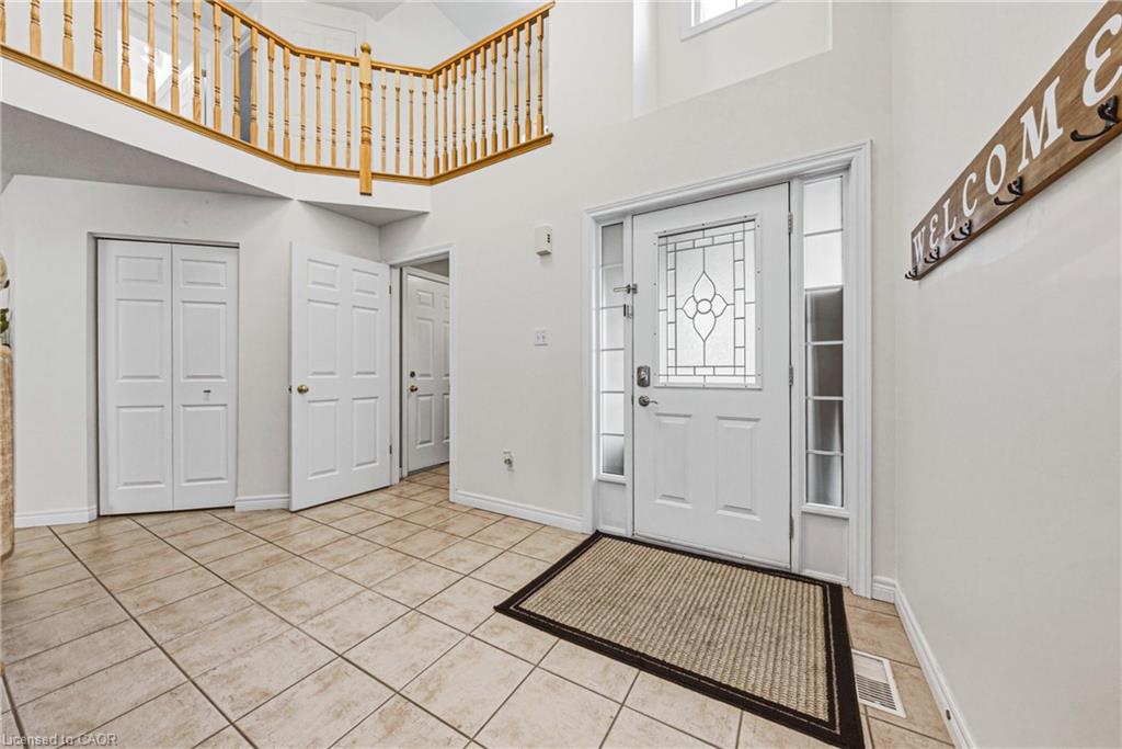 Double-height entryway featuring a white door with leaded glass, side-lite windows, and transom windows
