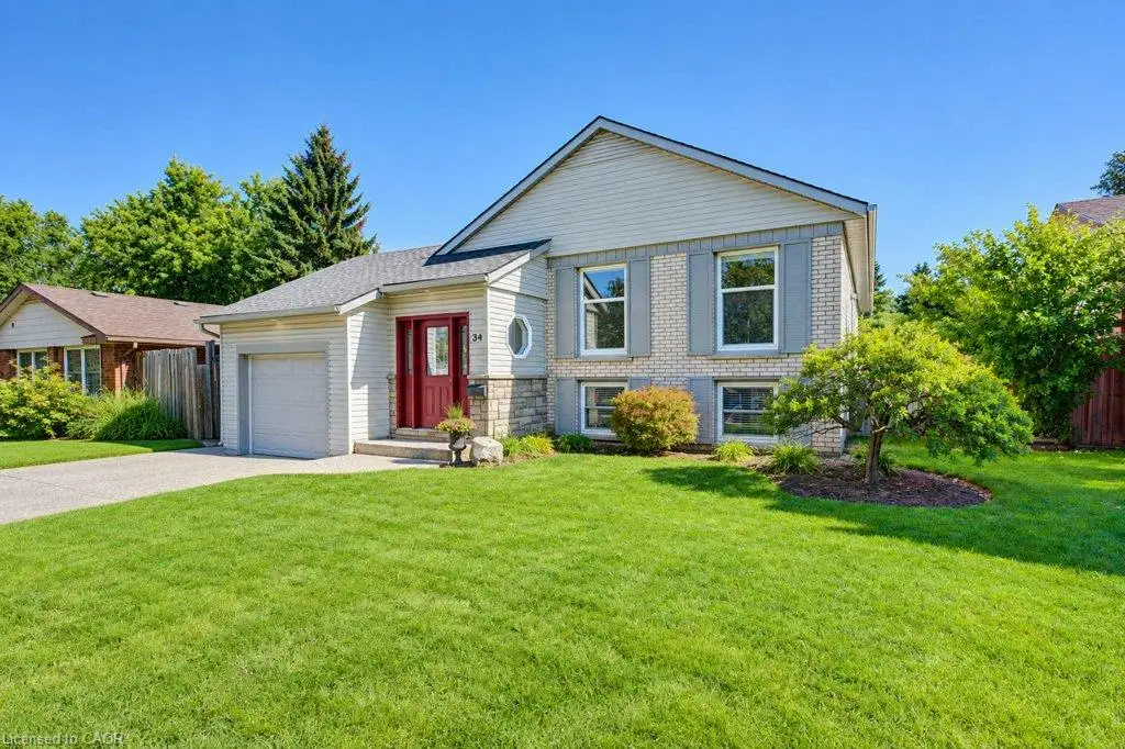 Split-level residence featuring a brick and siding exterior, an attached garage,  and a paved driveway