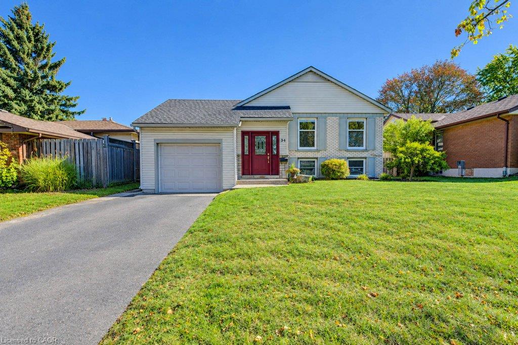 Great curb appeal featuring brick and siding, a two-car driveway, attached garage, and a red front entry door