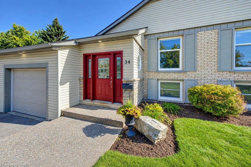 Brick and siding exterior with gray shutters, front door with sidelights, attached garage, and a concrete driveway