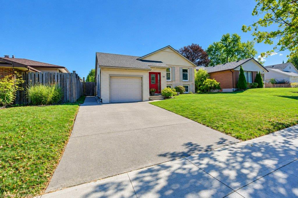 Lovely curb appeal featuring a single-car garage, concrete driveway, and a red entry door