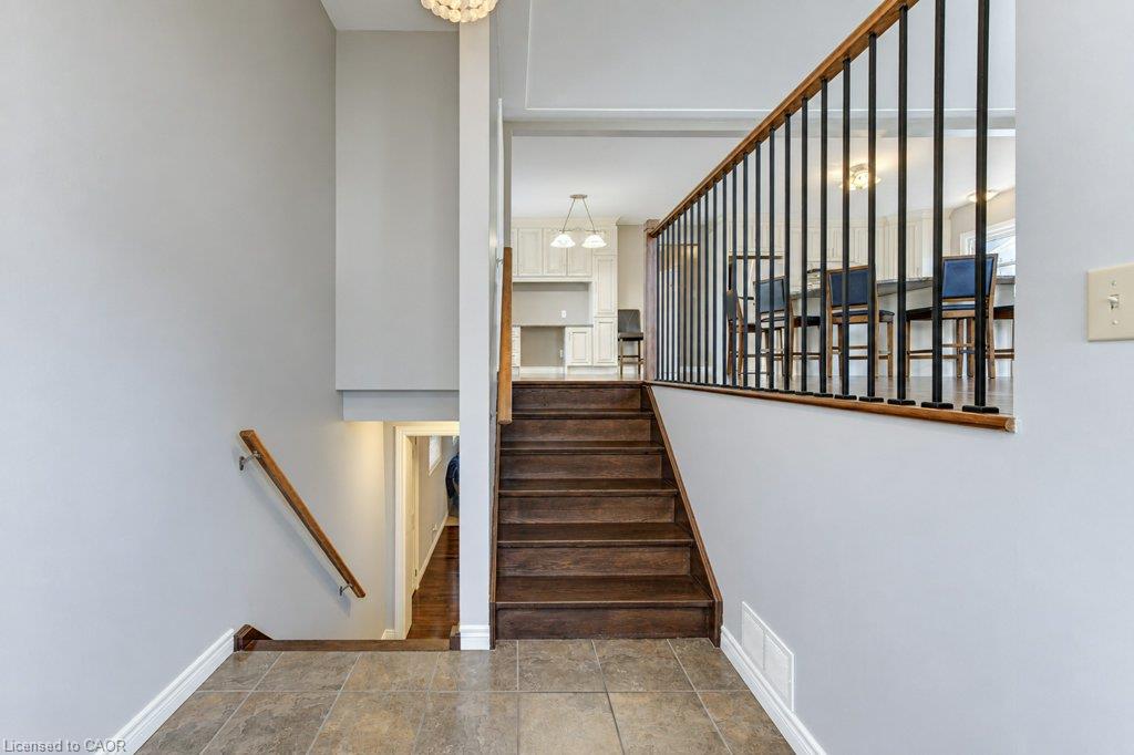 Entryway with tile flooring, wood-finish stairs, and metal balusters