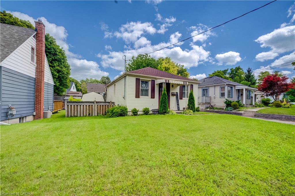 Expansive lawn with mature trees, a covered front porch, and a paved walkway