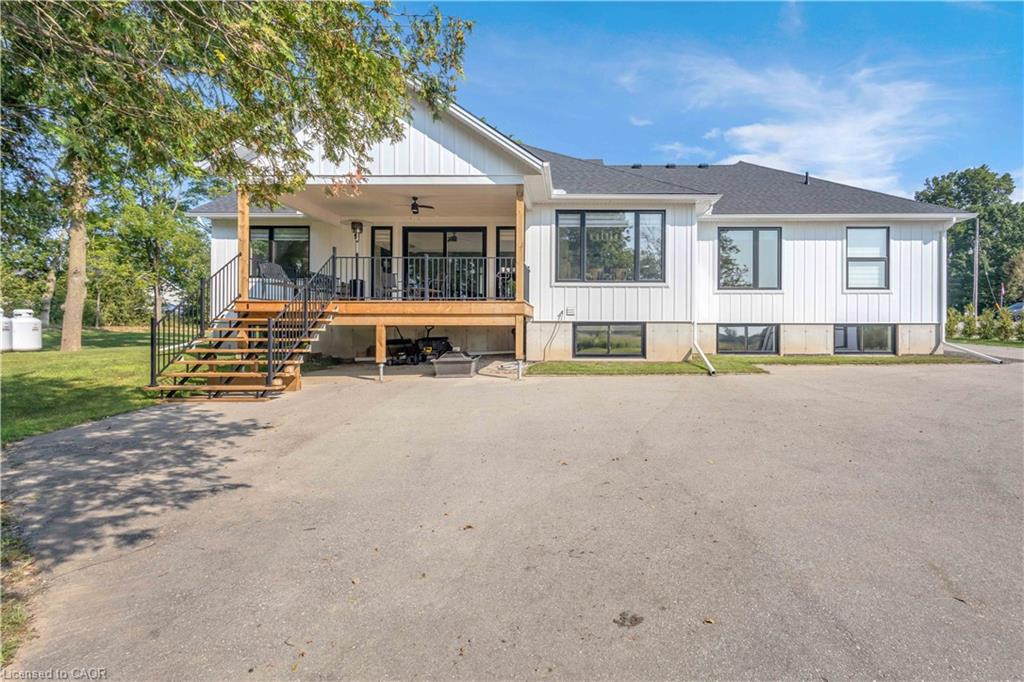 Modern manufactured home featuring a clean white exterior with metal siding, a sloped charcoal roof, and a covered front porch with wooden deck stairs and black metal railings