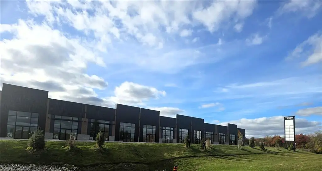 Commercial building exterior featuring dark metal paneling, expansive floor-to-ceiling glass storefronts, and a dedicated pylon signage structure