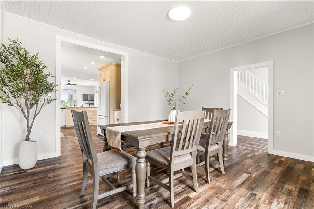 Wood-finish flooring, light grey wall paint, beadboard ceiling, white trim, and a white staircase with balusters