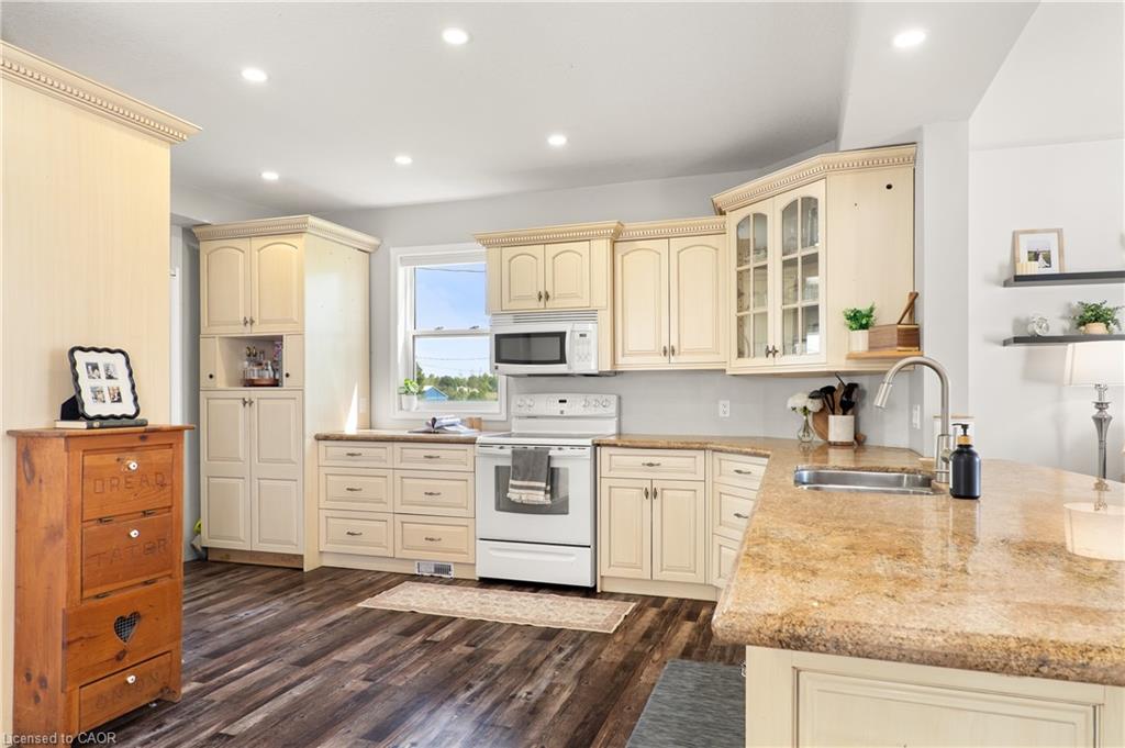 Kitchen featuring wood-finish flooring, recessed lighting, cream-colored cabinetry, light-toned countertops, and a stainless steel sink with a gooseneck faucet