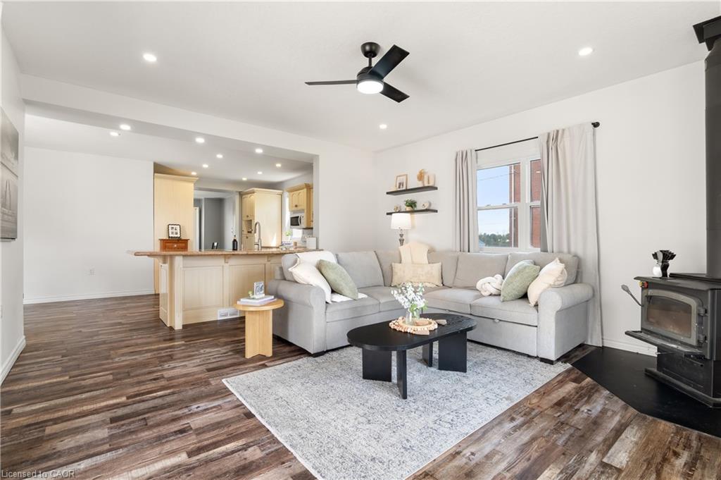 Wood-finish flooring throughout the living space and kitchen, featuring recessed lighting and a ceiling fan