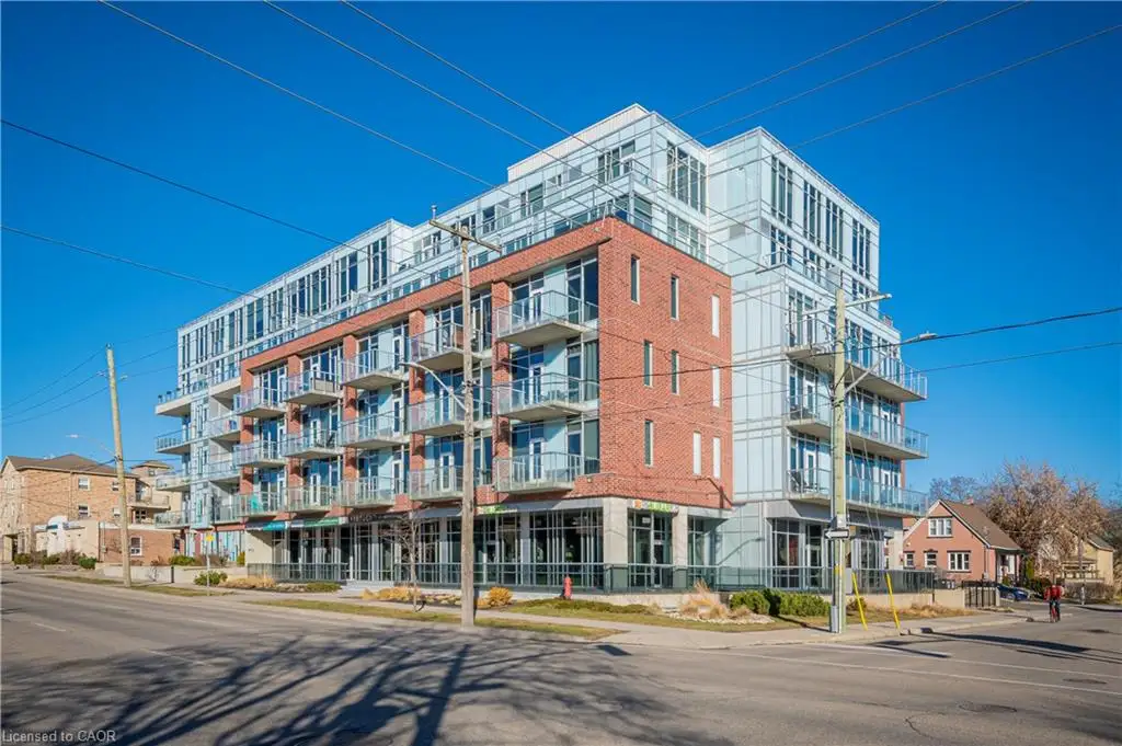 Contemporary multi-story building featuring a red brick facade with expansive windows, glass balconies, and a light-toned upper level