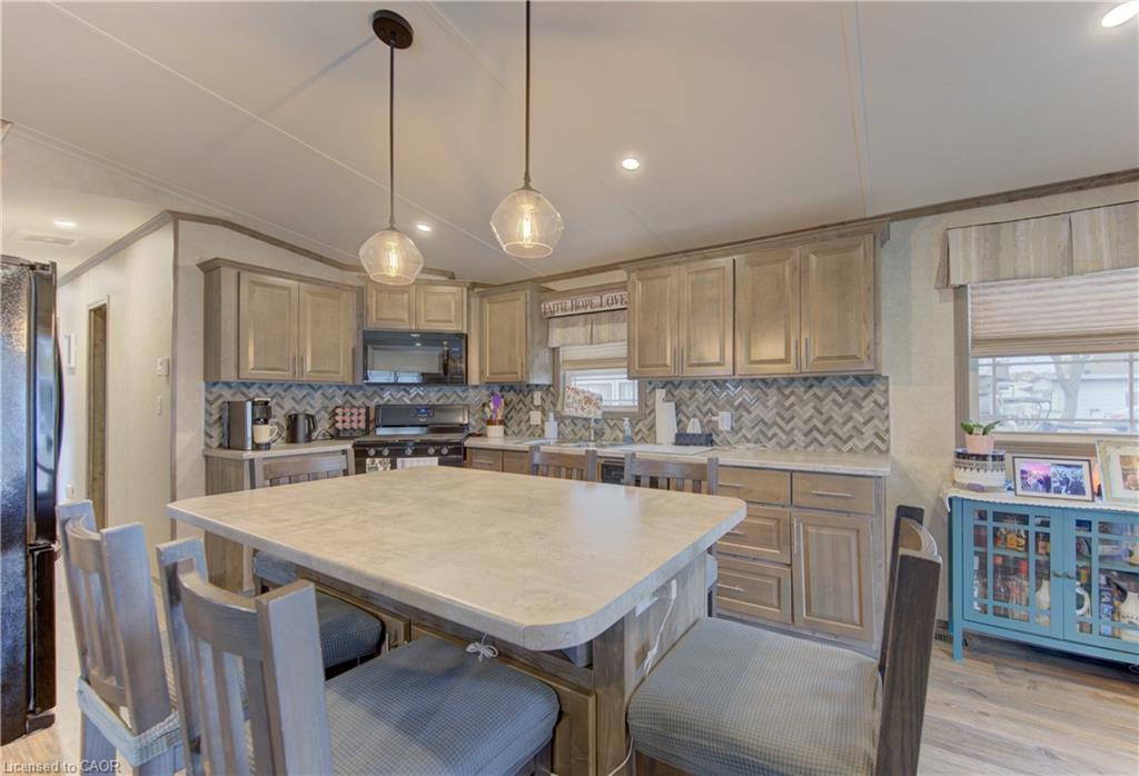Kitchen with L-shaped cabinetry, light-toned countertops, and a herringbone pattern tile backsplash