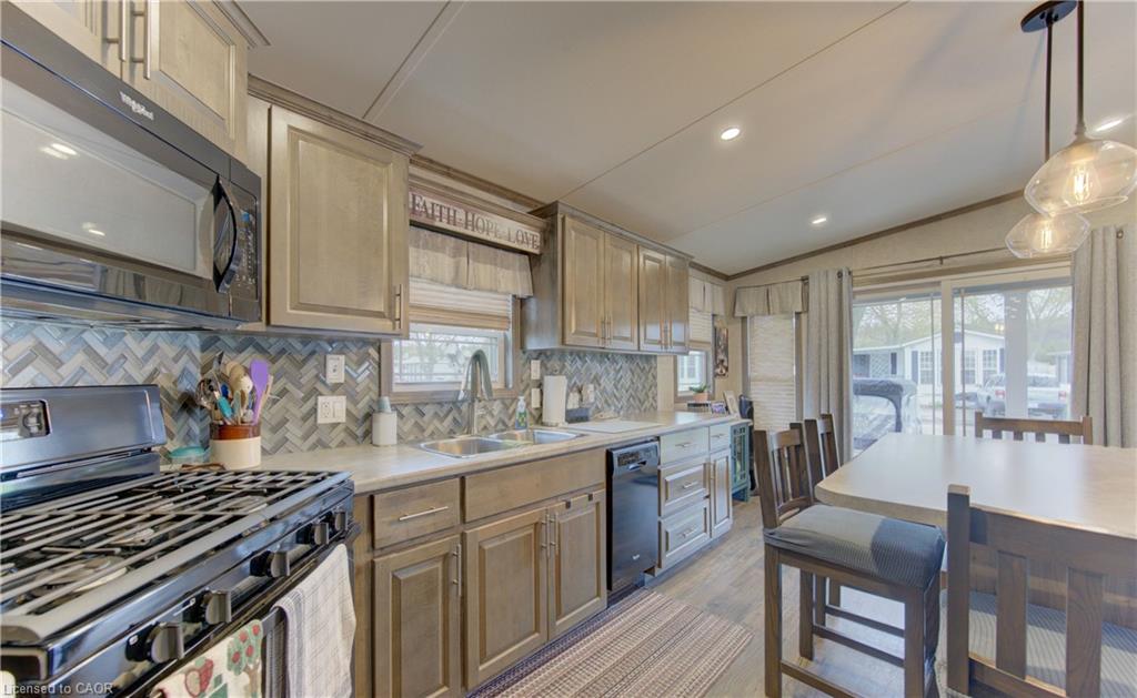 Modern kitchen featuring stainless steel appliances, a herringbone tile backsplash, and light-toned cabinetry