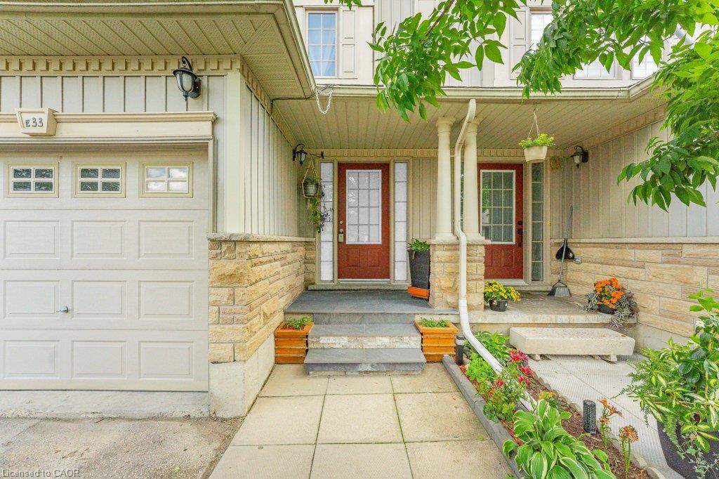 Exterior featuring a paneled garage door, stone veneer accents, and a covered porch with architectural columns