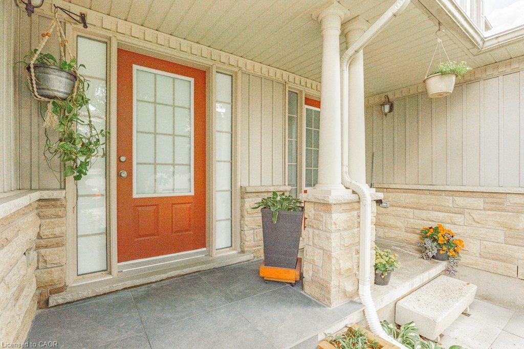 Entryway featuring a paneled door with glass inserts, sidelight windows, stone accents, and a covered porch