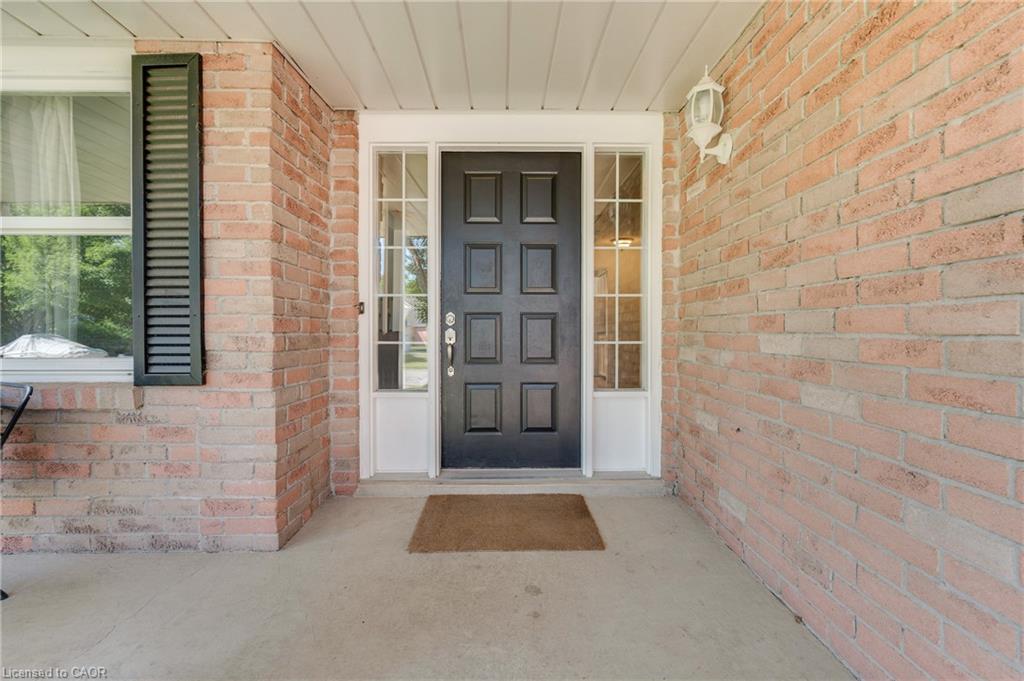 Brick exterior with a paneled black door, sidelight windows, and a covered porch entry