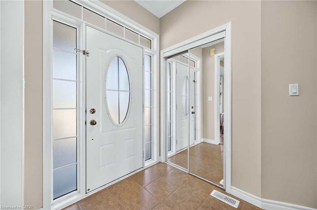 Entryway featuring a white paneled door with an oval window, frosted sidelight panels, a transom window, and tile flooring