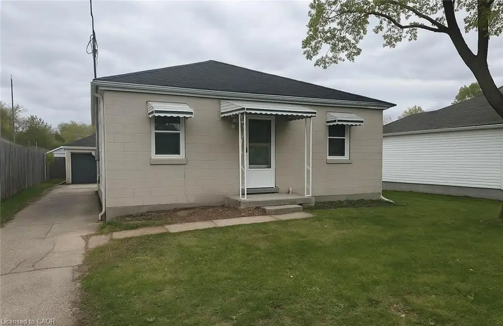 Single-story residence featuring a block exterior, covered entry, and a paved driveway leading to a detached garage