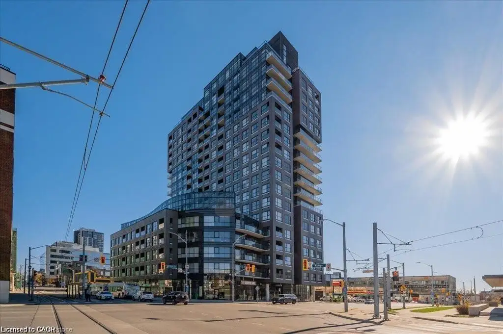 Contemporary high-rise building featuring a dark facade with expansive windows, multiple balconies, and a distinctive curved glass section at its base