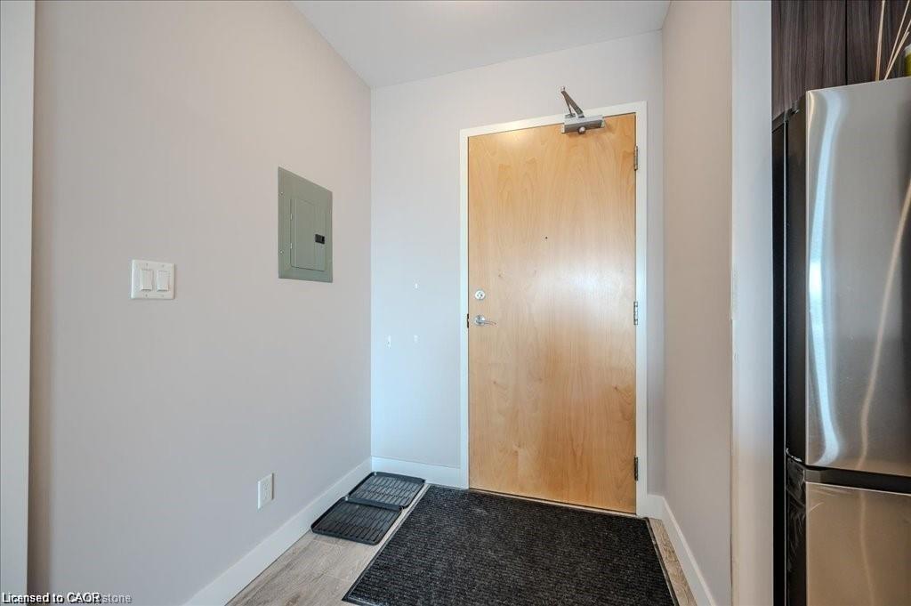 Entryway featuring a natural wood-finish door, light wood-finish flooring, and a stainless steel refrigerator