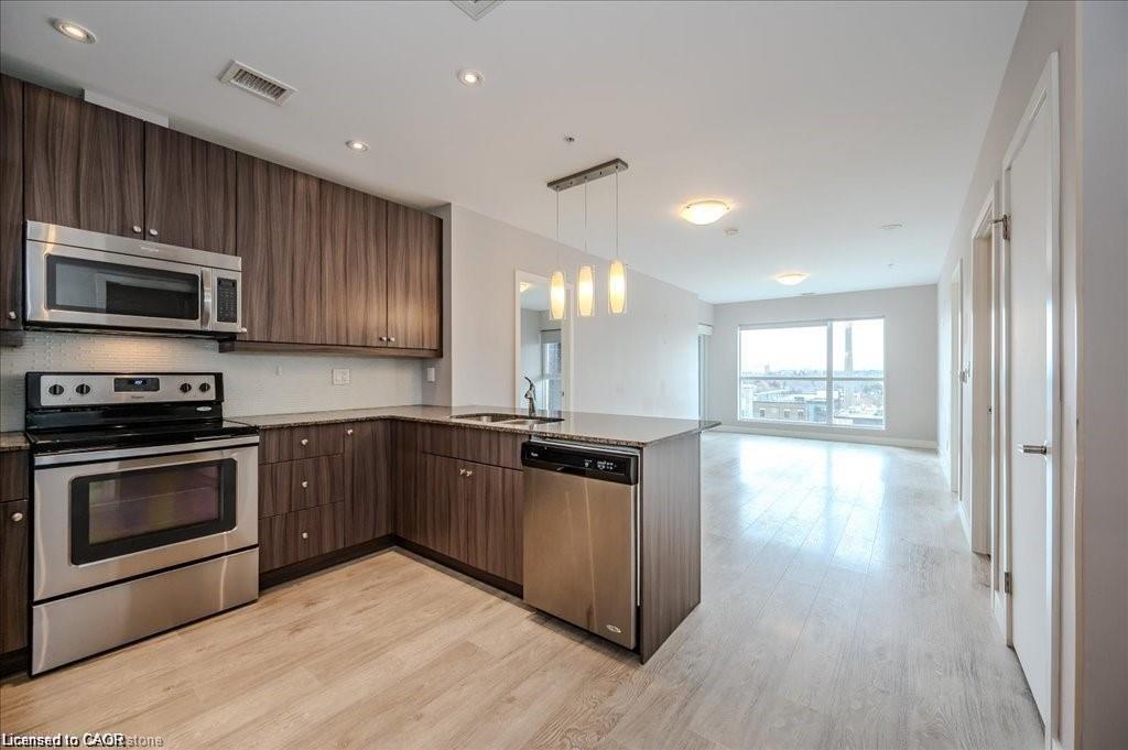 Modern kitchen featuring wood-finish cabinetry, stainless steel appliances, recessed lighting, and a peninsula with pendant lighting