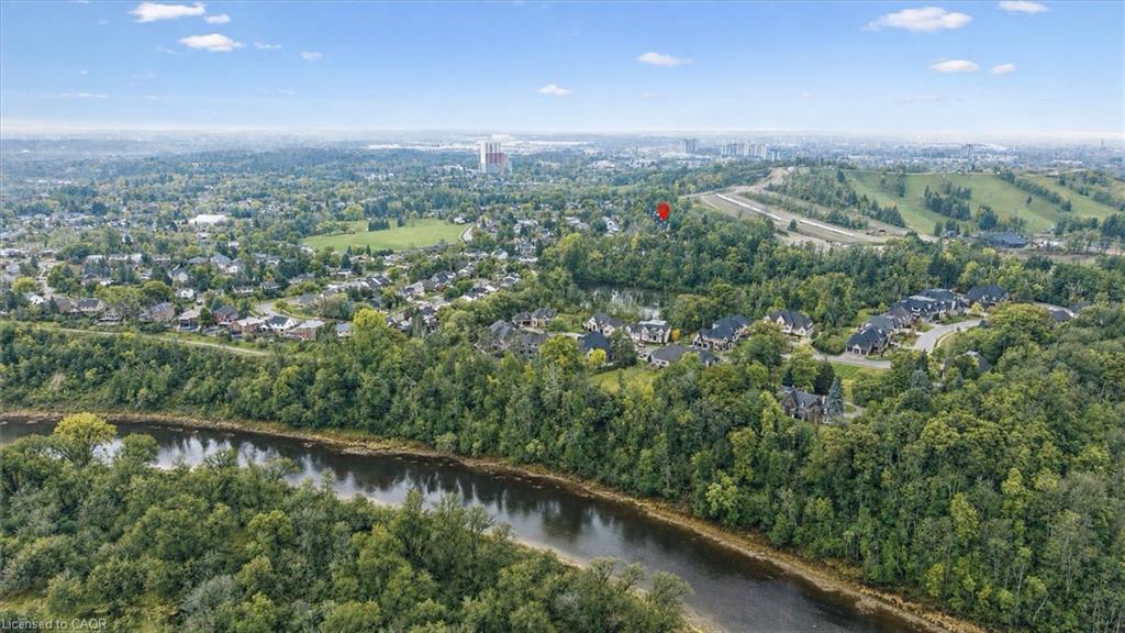 Riverfront properties surrounded by mature trees, with city infrastructure visible in the distance